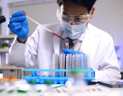 Asian scientist doing some research and looking through a microscope in laboratory.